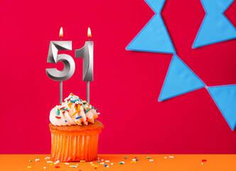 Birthday cupcake with candle number 51 on a red background with blue pennants
