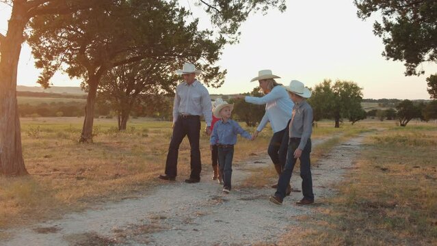 A family of five walk their farm land at sunset