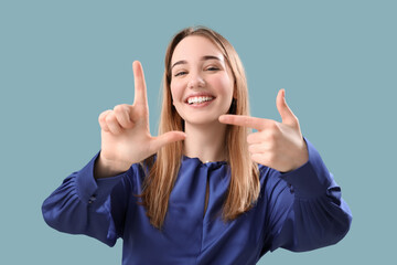Young woman showing loser gesture on blue background