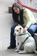 A 40-year-old Latina woman spends time in the park with her emotional support dog who accompanies her to make her feel better about her emotional or psychological difficulties