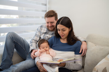 FAMILY DAY. Mother's Day. Family with pet. Young parents mom and dad show didactic cards to their baby daughter.