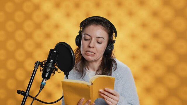 Narrator wearing headphones, reading aloud from book into microphone, exhaling after finally finishing job. Person recording audiobook, creating engaging media content for listeners, camera A