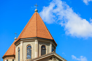 Fototapeta na wymiar A church steeple with a red roof and two crosses on top
