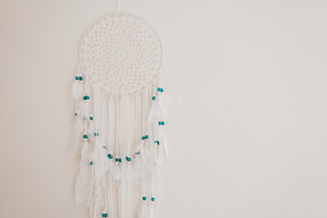 Dream Catcher with white feathers and blue beads on a beige wall.Wicker talisman protects against bad dreams. Decoration for home and room. Macrame wall decoration 