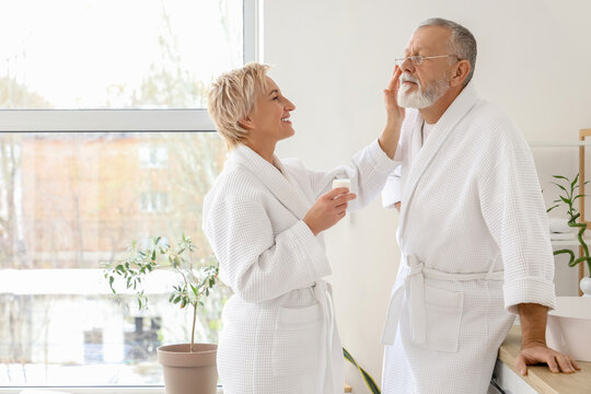 Mature couple applying facial cream in bathroom - Powered by Adobe