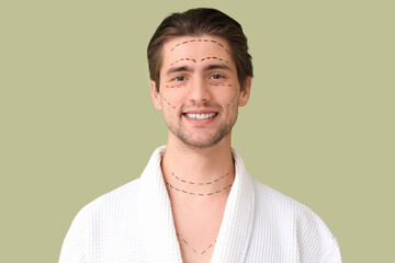 Smiling young man with marked face on green background, closeup. Plastic surgery concept