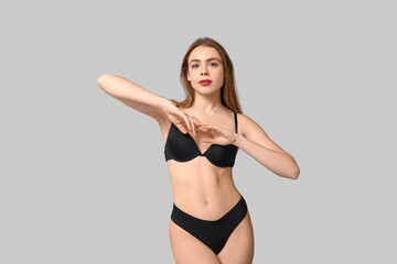 Attractive young woman in black underwear on light background