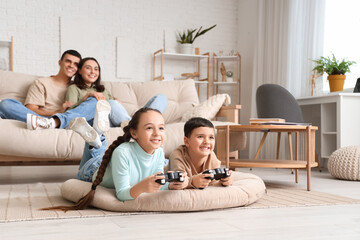 Little children playing video game and his parents at home - obrazy, fototapety, plakaty