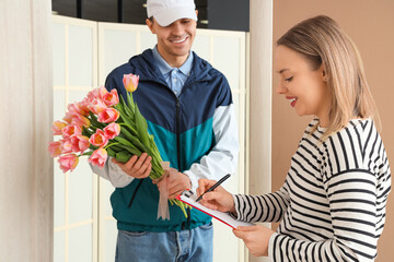 Young woman receiving bouquet of tulips from courier at door