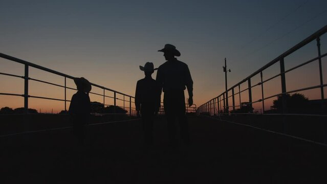 Silhouette shot of young farmers clipping on pasture gates to watch the sunset