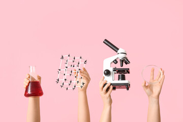 Female hands holding microscope with molecular model, filled flask and Petri dish on pink...