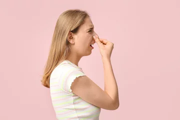 Foto op Canvas Young woman pinching nose because of bad smell on pink background © Pixel-Shot