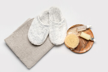 Grey slippers, towel and cosmetic products on grey background. Top view