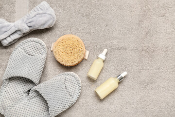 Grey slippers and cosmetic products on grey towel. Top view