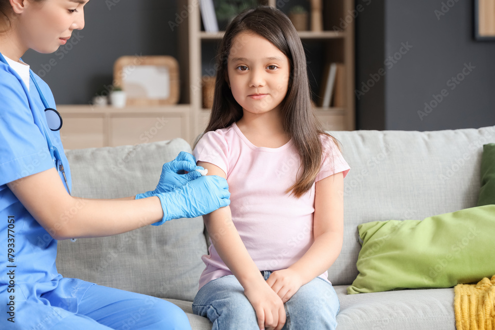 Wall mural doctor pressing gauze on little girl's arm after vaccination at home