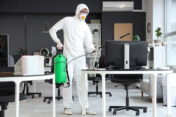 Male worker disinfecting workplace in office