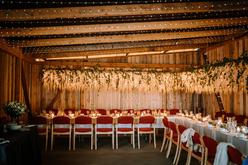 Valmiera, Latvia - August 10, 2023 - Rustic wedding venue with wooden walls, fairy lights, floral...