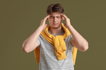 Portrait of young man suffering from headache on green background