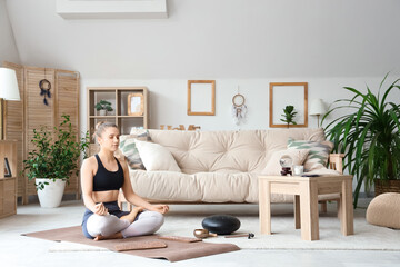 Sporty young woman with Sadhu board meditating at home