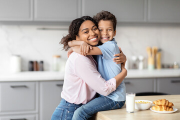 Son giving his mother a loving hug in kitchen
