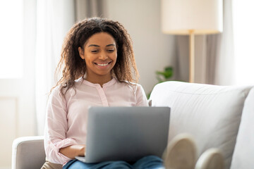 Lady with laptop smiling warmly at home