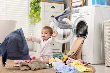 Little girl scattering baby clothes in bathroom