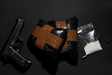 Drug packages with gun and bullets on dark background