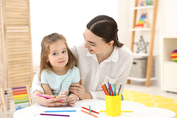 Mother and her little daughter drawing with colorful pencils at home