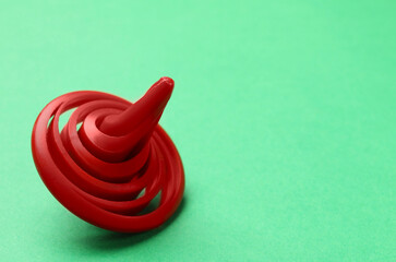 One red spinning top on green background, closeup. Space for text