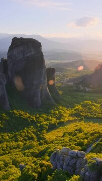 Sunset over monastery of Rousanou and Monastery of St. Nicholas Anapavsa in famous greek tourist destination Meteora in Greece with sun rays and lens flare. Horizontal camera pan