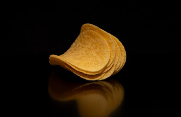 Close-up with a group of potato chips on a black background, perfect as a decorative or ornamental image
