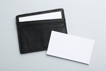 Leather business card holder with blank cards on light grey background, top view