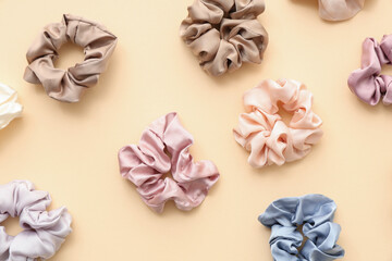 Trendy silk scrunchies on light yellow background