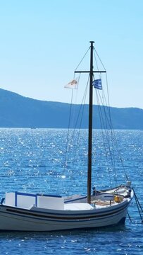 Traditional fishing boat in the Aegean sea with Greek flag, Milos island, Greece
