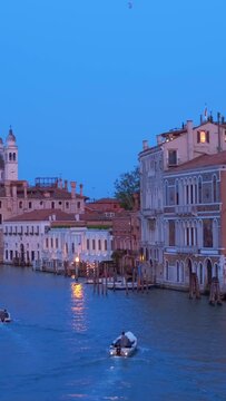 View of Venice Grand Canal with boats and Santa Maria della Salute church in the evening from Ponte dell'Accademia bridge. Venice, Italy. Horizontal camera pan
