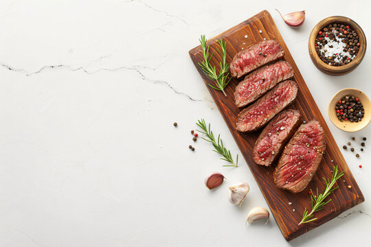 medium rare steak on the old wooden cutting board, ready to cook, marble background, top view, copy space
