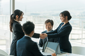 企業のオフィス・会議室で握手をして契約を結ぶビジネスウーマン
