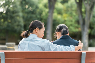 ベンチで落ち込む・ショックを受ける中学生・高校生の女の子を励ます・慰める女性教師・母親（トラブル）
