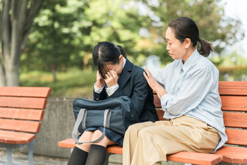 ベンチで落ち込む・ショックを受ける中学生・高校生の女の子を励ます・慰める女性教師・母親（トラブル）
