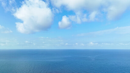 Boundless sea unfolds beneath as drone glides through azure waves, framed by a canvas of blue sky...