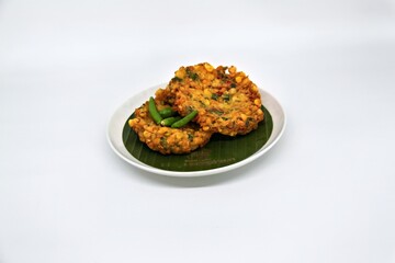 Bakwan Jagung or Dadar Jagung or Dadar Jagung Manado, is Manadonese style of corn fritters. Savoury snack made of corn, egg, flour, spring onion, pepper and salt. Served on a wooden plate.