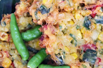Bakwan Jagung or Dadar Jagung or Dadar Jagung Manado, is Manadonese style of corn fritters. Savoury snack made of corn, egg, flour, spring onion, pepper and salt. Served on a wooden plate.