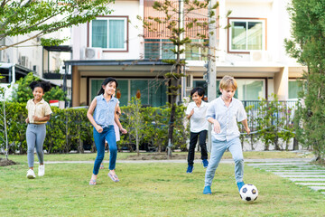 Group of young children playing football outdoors in the school garden. 