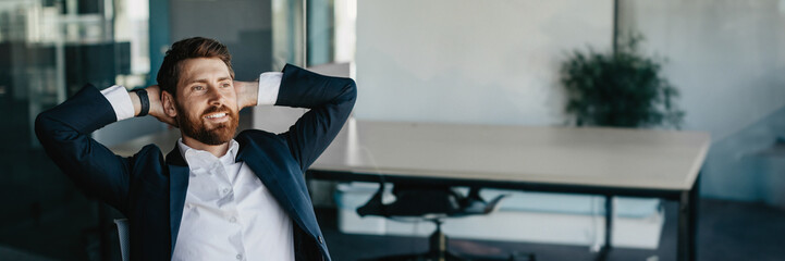 Excited businessman relaxing on chair, leaning back at workplace