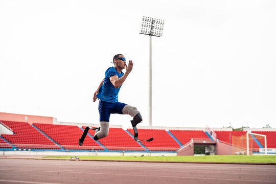 Asian para-athletes disabled with prosthetic blades running at stadium. 