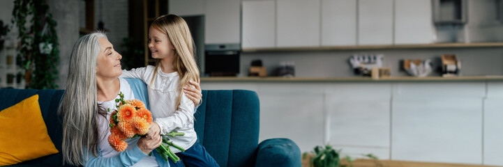 Cheerful little girl hugs european elderly lady