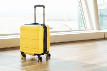 Yellow luggage bag on wheels at the airport, side view.