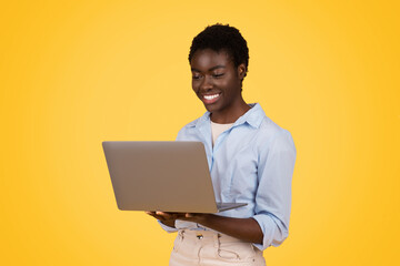 Young black lady professional with laptop on yellow
