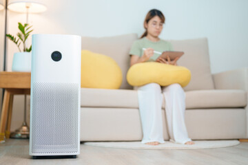 Air Purifier with woman relax and use tablet on sofa. Purification system for filter and cleaning dust PM2.5 HEPA and virus in home. Allergy, Pure air, health, Wellness lifestyle and Air Pollution