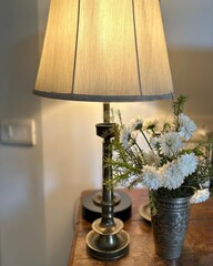 Table lamp and flower in vase on wooden table in living room